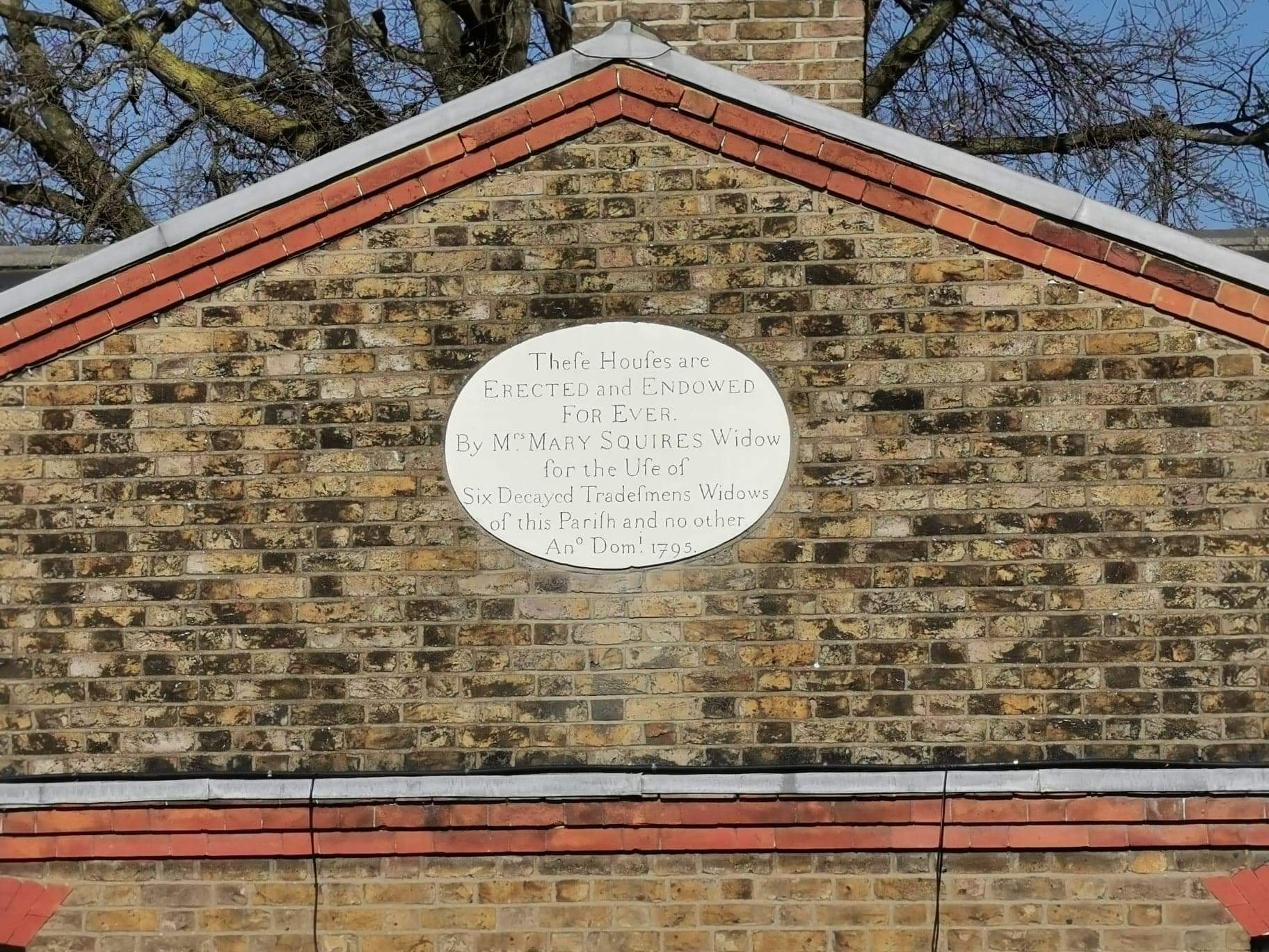 The plaque on the front of the almshouses