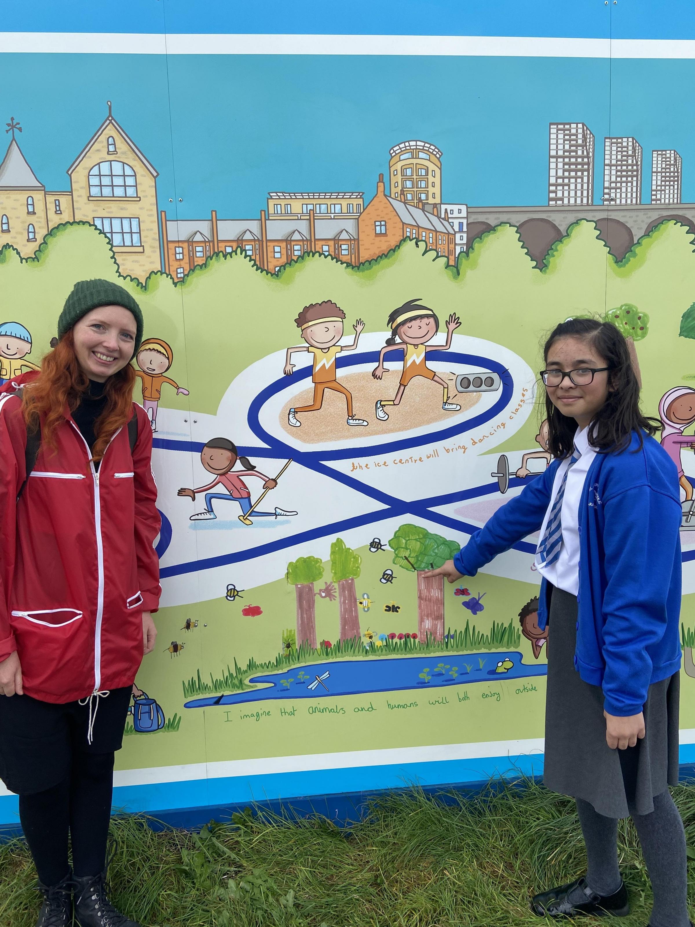 Artist Alice Druitt with Sarah, 10 from St Joseph’s Catholic Junior School who is pointing at her trees which contributed to the final hoarding artwork.