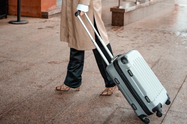 A person pulling a suitcase (Canva)